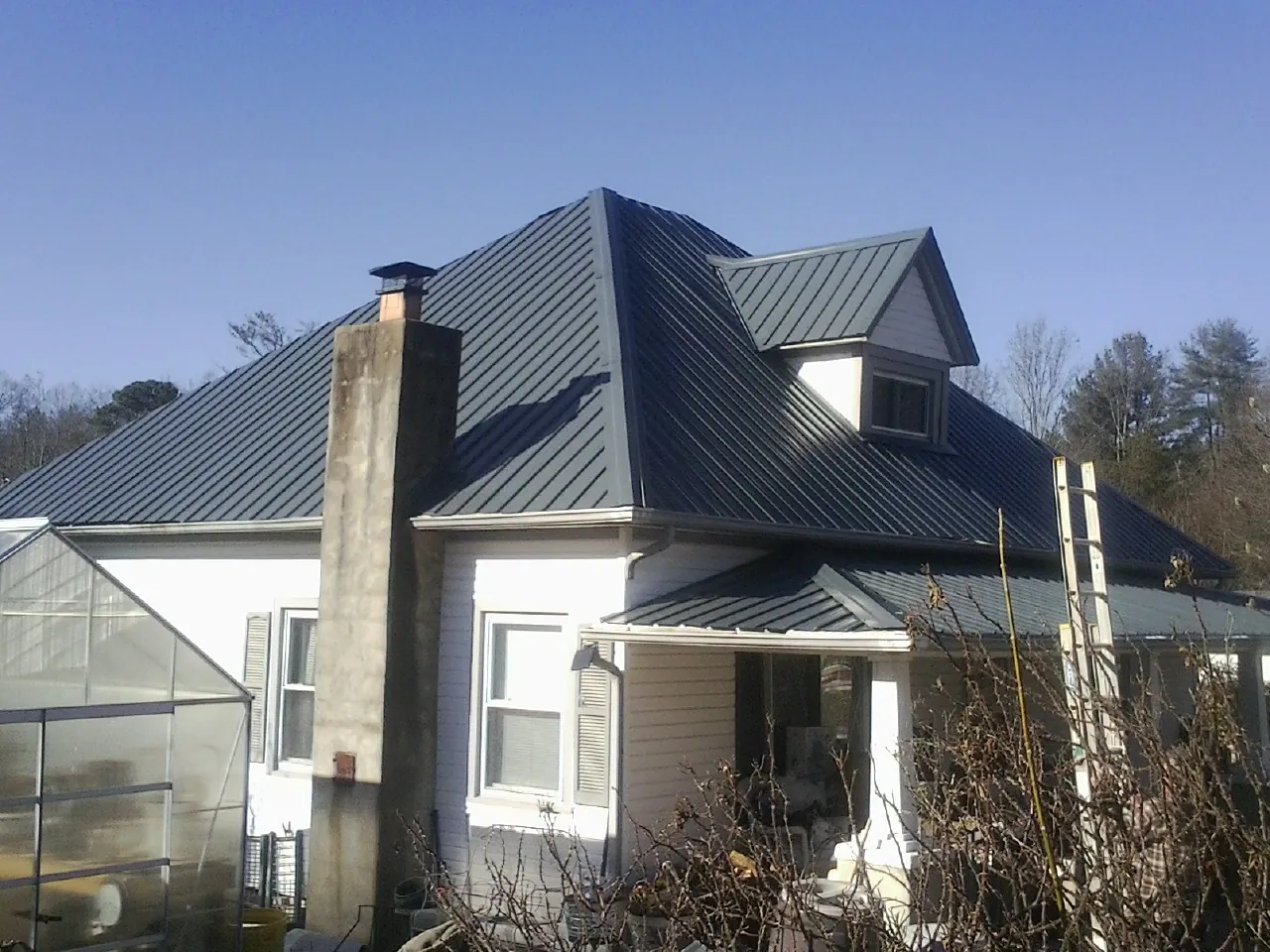 Dark blue standing seam metal roof on a white farmhouse with dormer — Slate & Tile Roof Repair by Roofing Brothers in Cleaton