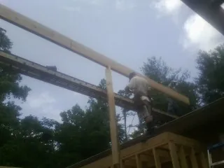 Carpenter setting a ridge beam over a new addition frame — Ice Dam Removal by Roofing Brothers in Cleaton