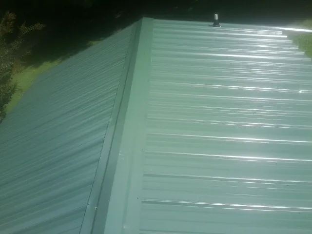 New green metal panels meeting at the ridge of a roof — Flat Roof Repair work by our crew in Cleaton