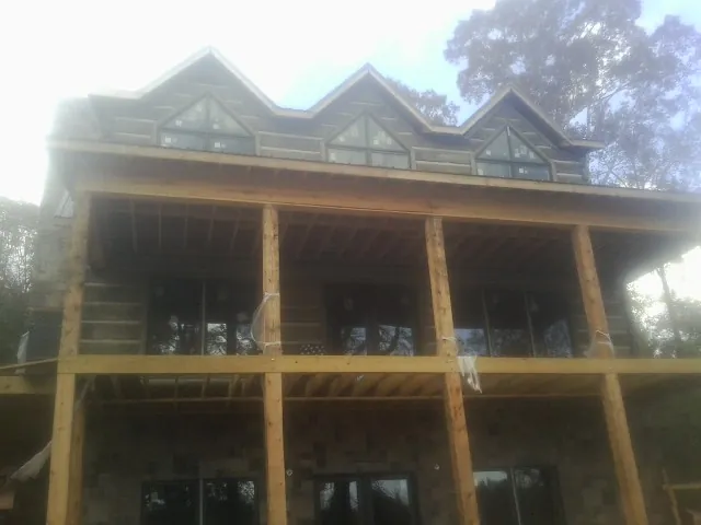 Dormers and porch framing on a large log home under construction — Roof Coating work by our crew in Cleaton