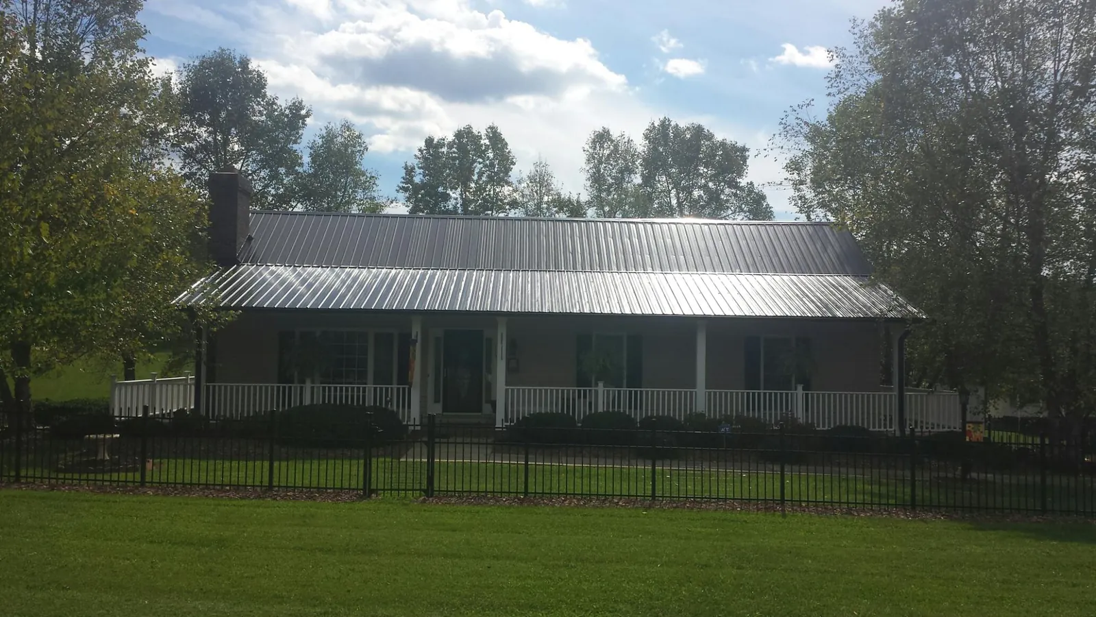 Gray metal roof on a brick ranch with a full width front porch — Gutter Guard Installation work by our crew in Cleaton