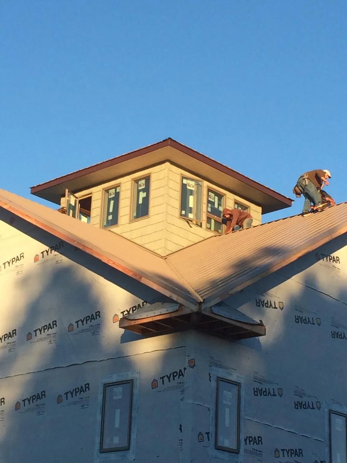Roofers working around a rooftop cupola on a new metal roof at sunset — Roof Waterproofing in Cleaton by Roofing Brothers